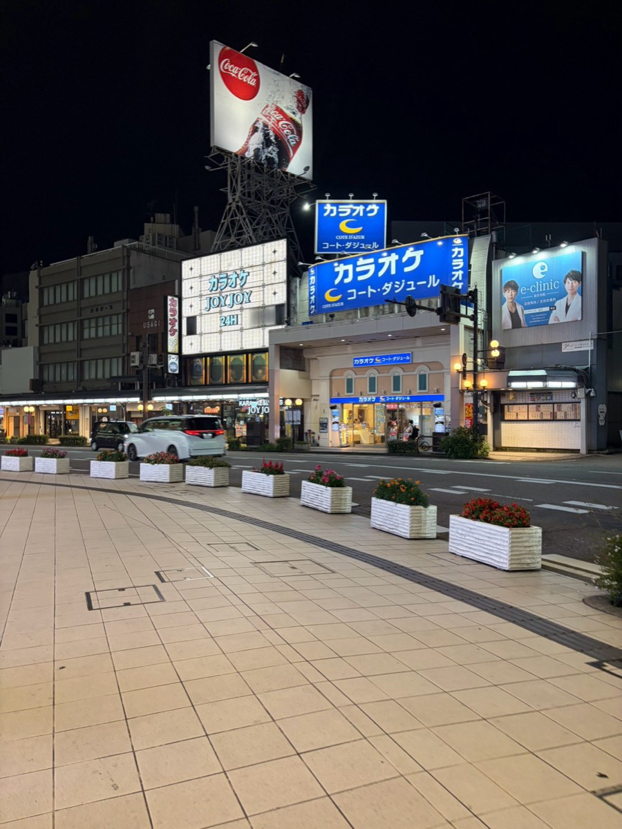 夜の片町、カラオケ店の看板が並ぶ通り。大型の丸看板が光っている