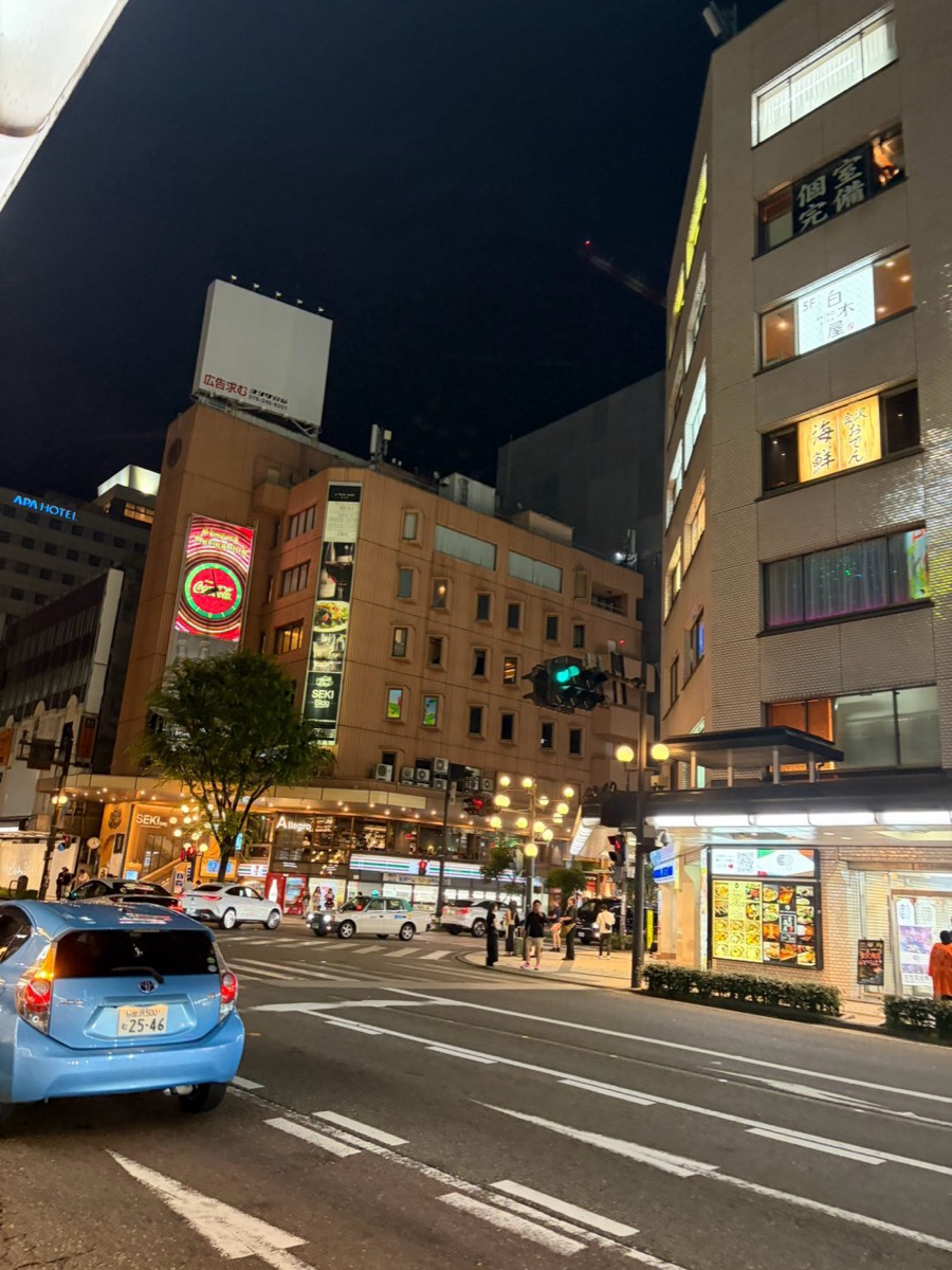 夜の片町交差点。雑居ビルの壁面に「個室完備」などの縦看板が並んでいる