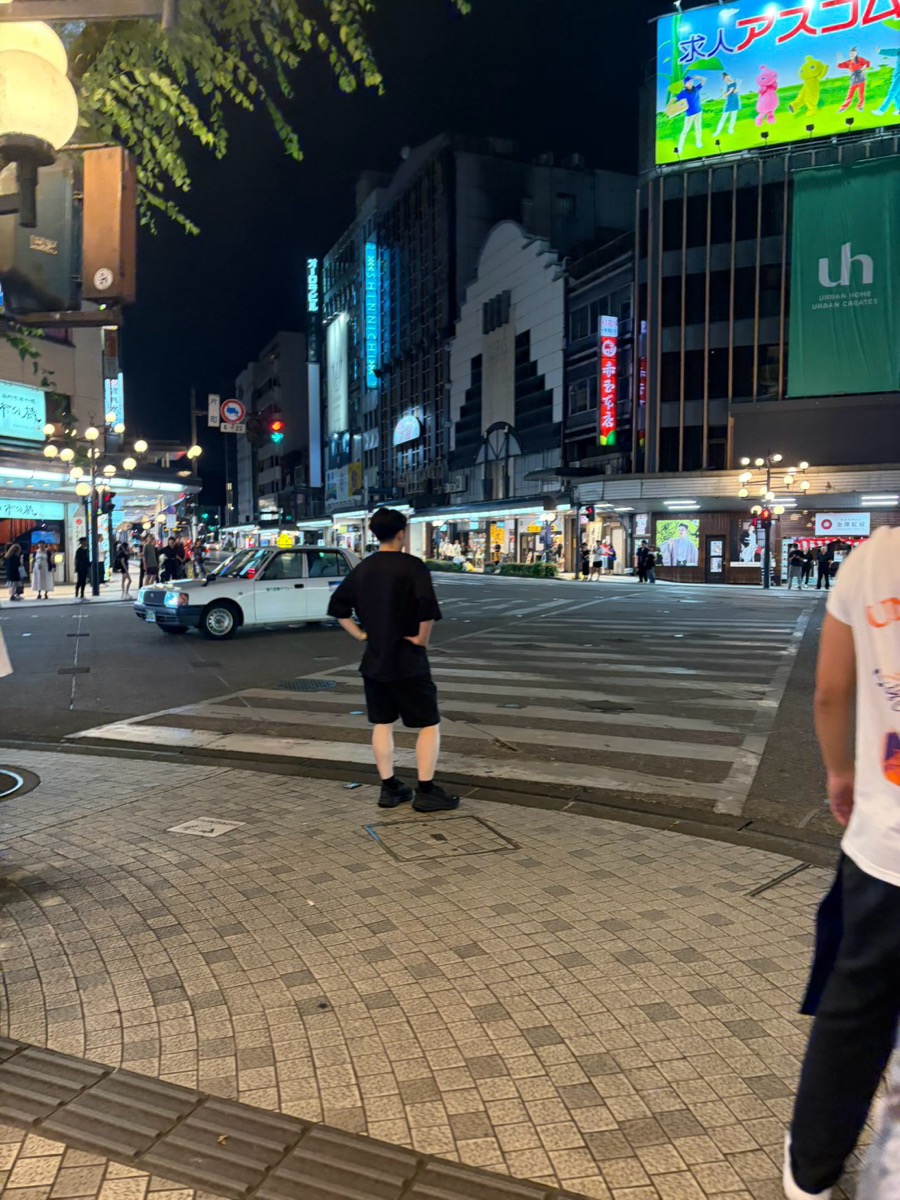 夜の片町スクランブル交差点。横断歩道の前で信号待ちをする人たち