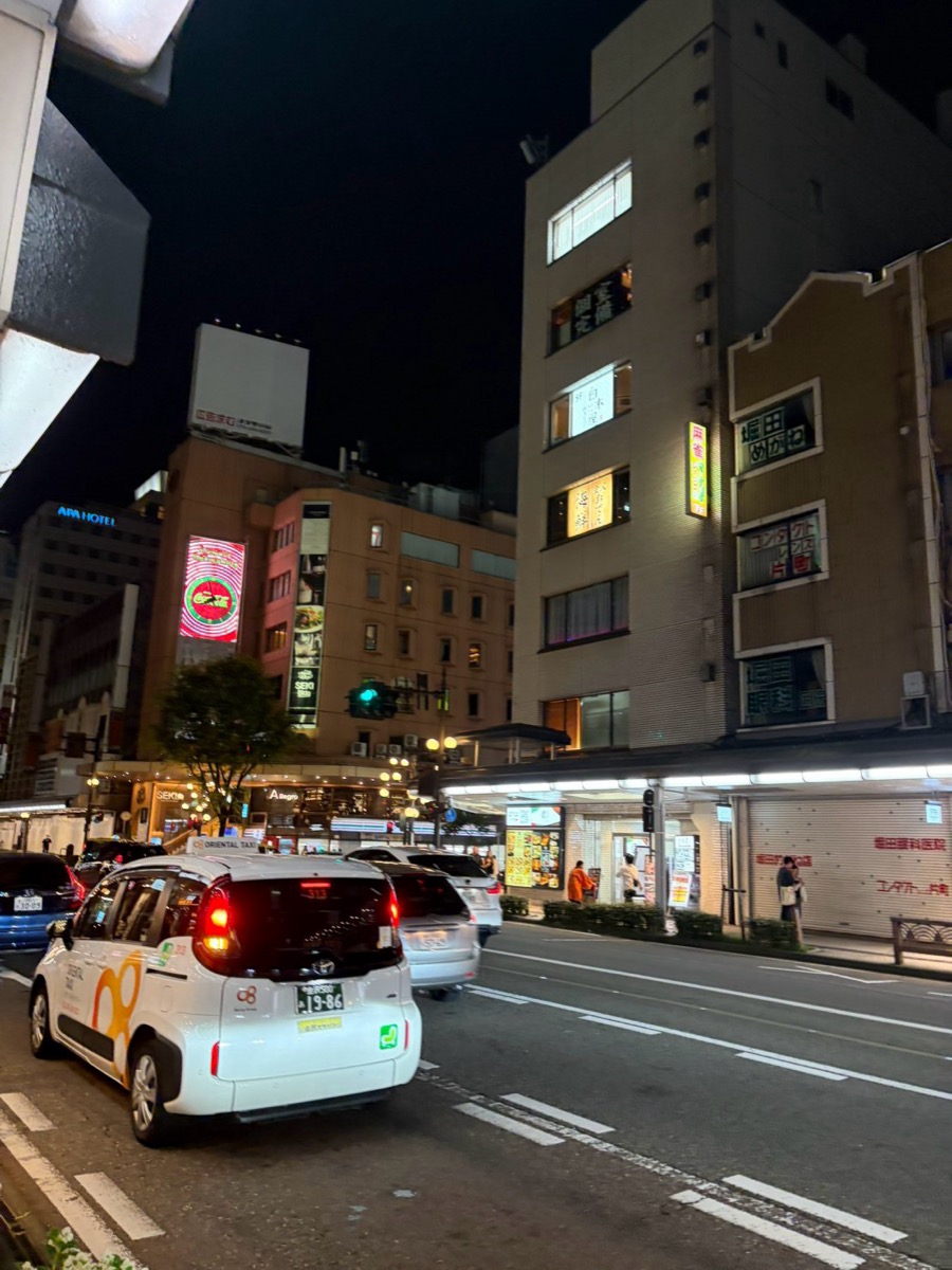 夜の片町交差点でタクシーが客待ちしている様子。周囲に店の看板が光る